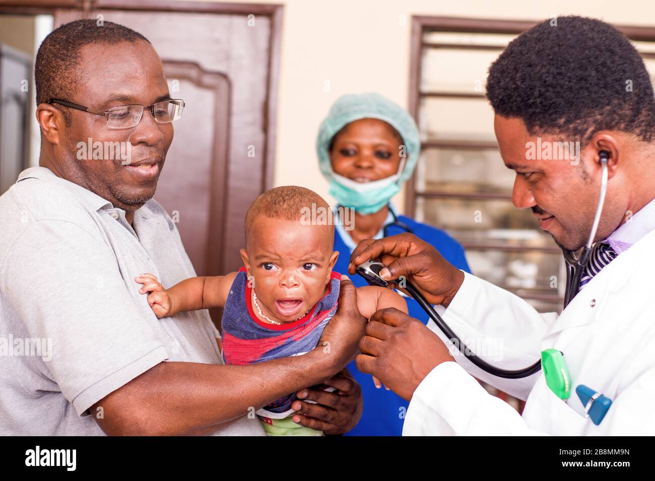 a young man catches his baby during the doctor examines him at the hospital. Stock Photo