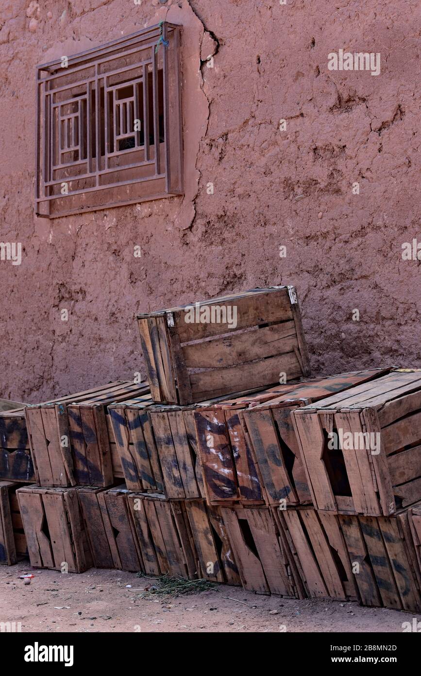 Empty wooden boxes for fruit and vegetables stacked against a typical, rustic Moroccan mud wall, Northern Africa. Stock Photo