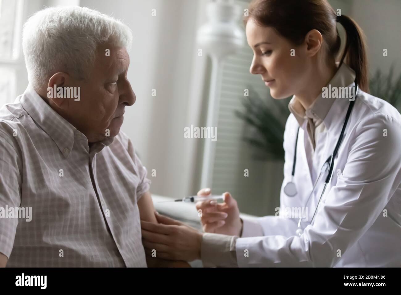 Nurse holding syringe makes an injection to elderly patient Stock Photo