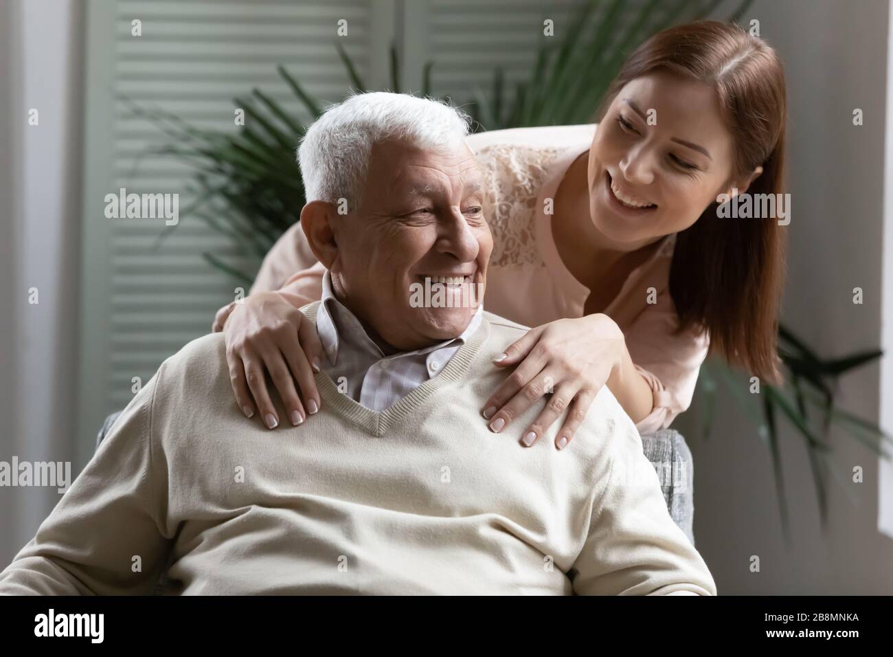 Caring adult granddaughter hugging elderly 80s grandfather Stock Photo