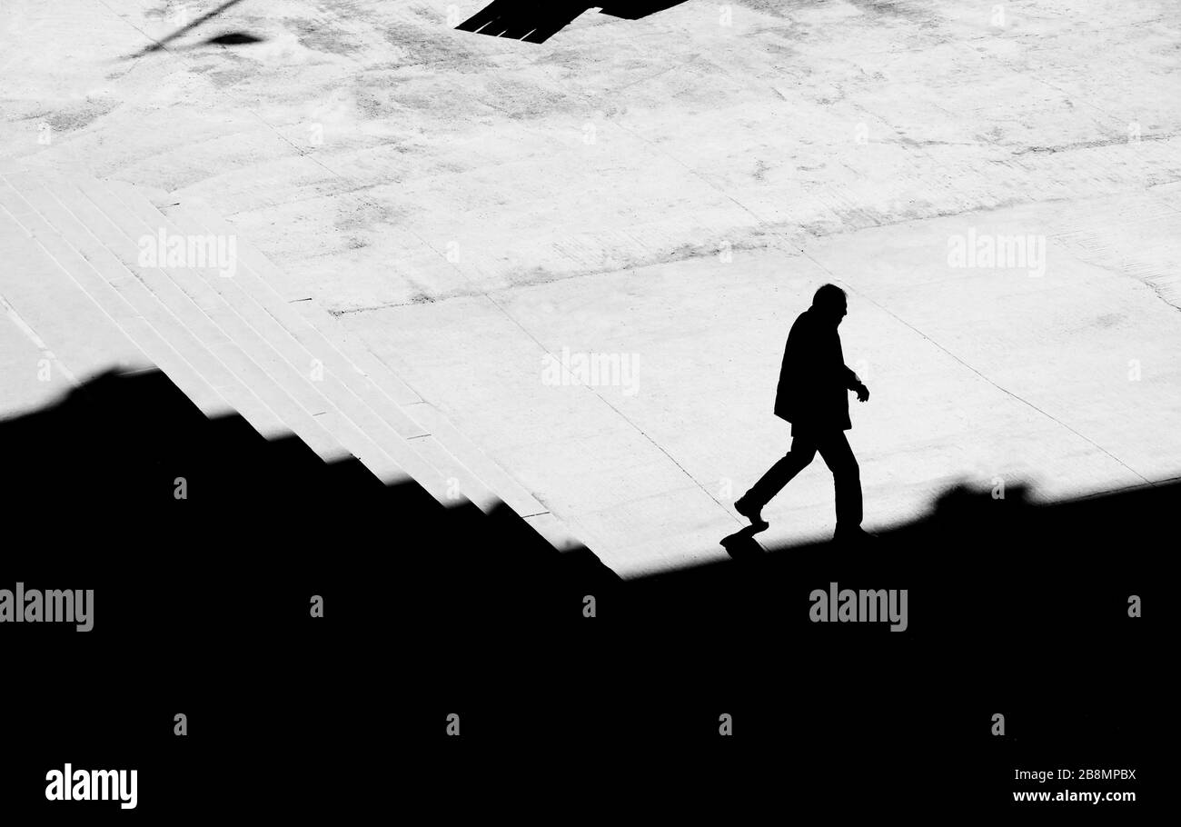 Shadow silhouette of a man walking alone down city stairs,  high angle view Stock Photo