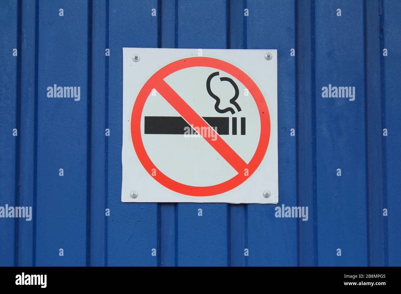 On the blue wall there is a white sign with an inscription prohibiting smoking. The concept of health and prohibition. Stock Photo