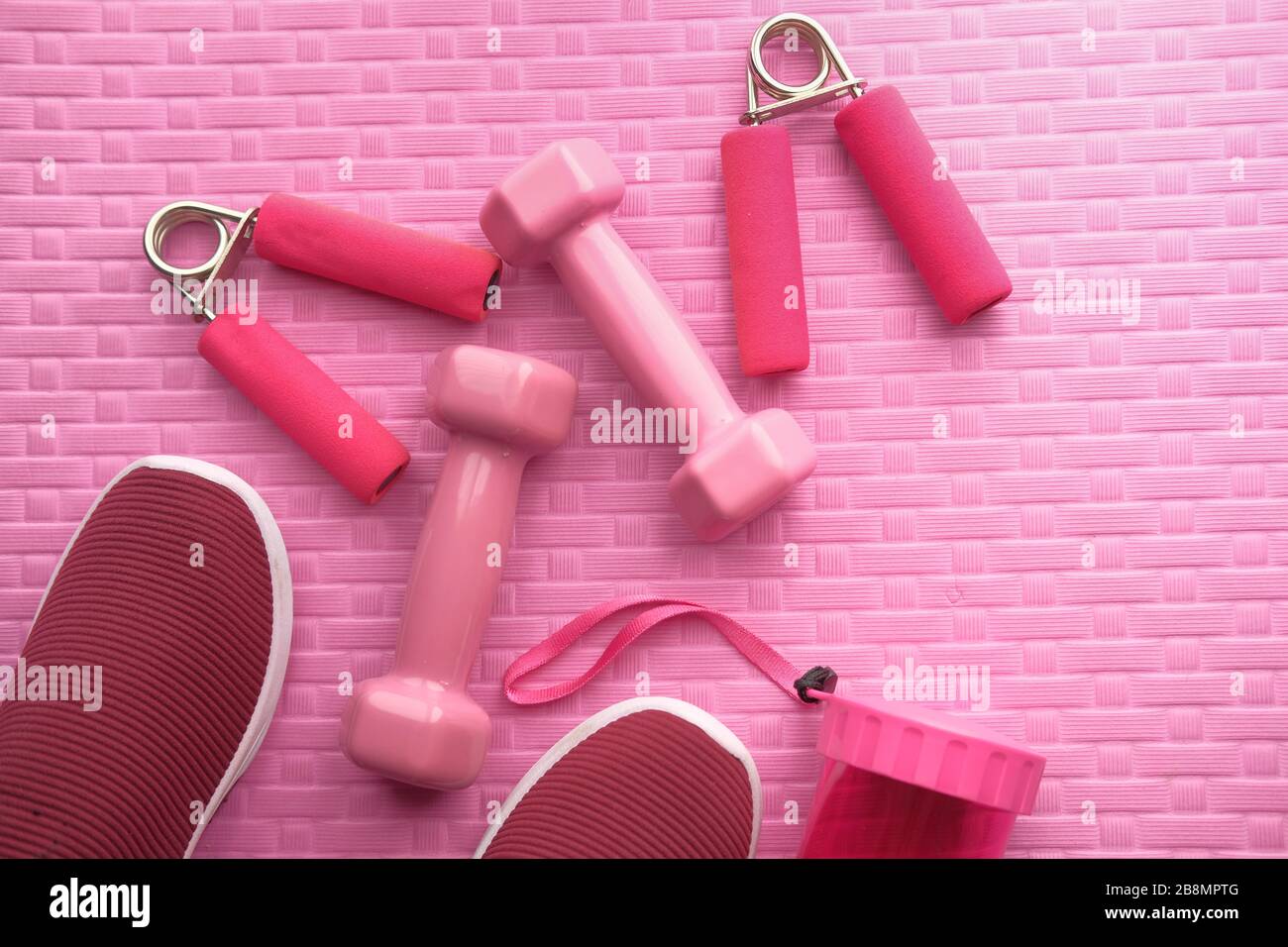 https://c8.alamy.com/comp/2B8MPTG/yoga-mat-with-sport-shoes-and-dumbbells-on-pink-background-2B8MPTG.jpg