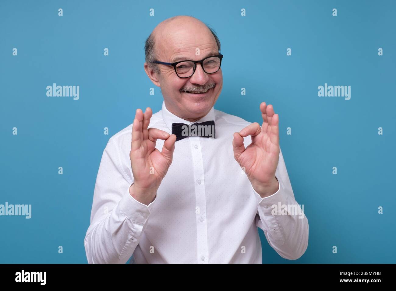 Caucasian man in white shirt smiling on camera with alright ok sign Stock Photo