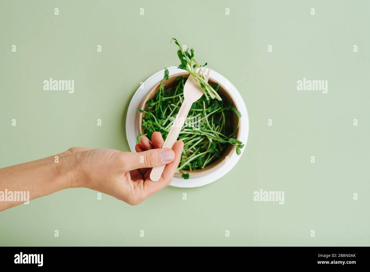 Hand with cornstarch fork, and eco-friendly disposable plate with peas Stock Photo
