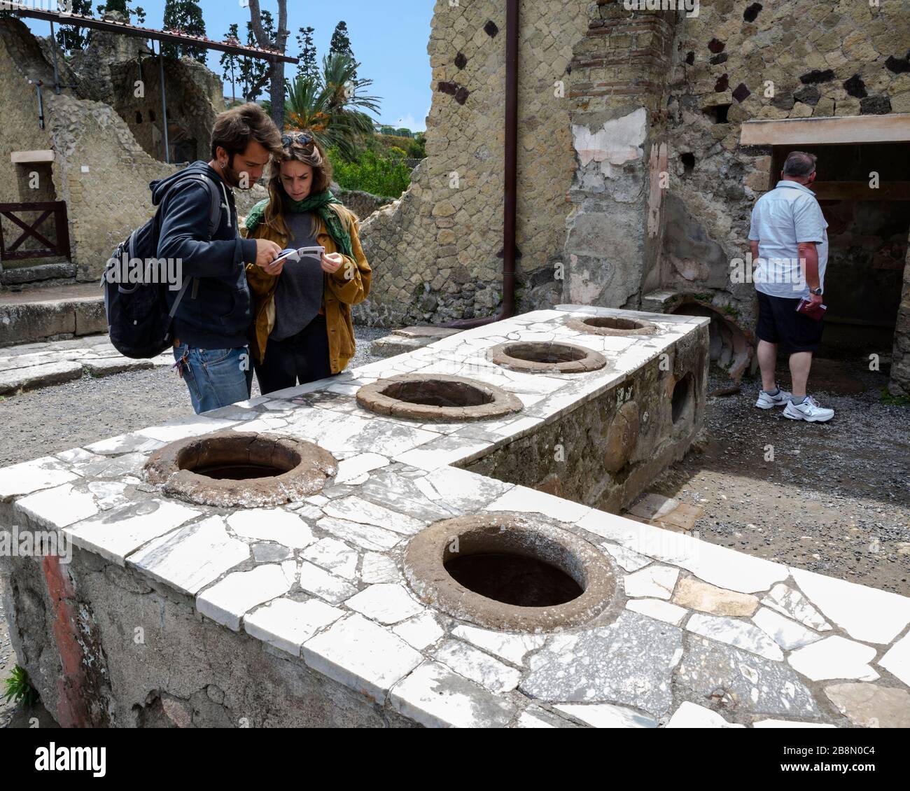 Tourists exploring the ruins of an ancient fast food shop, Herculaneum, Campania, Italy. Stock Photo