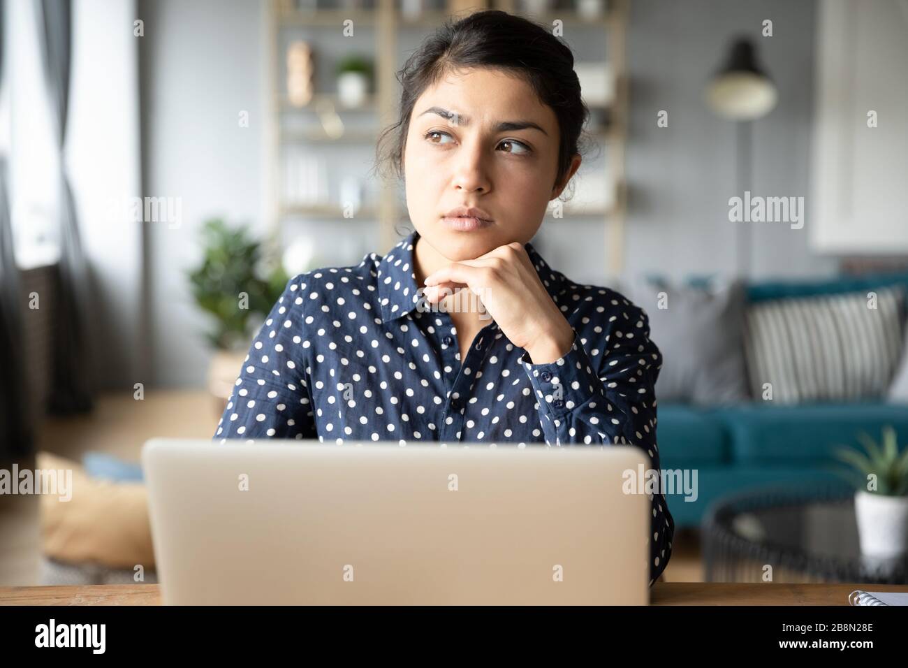 Thoughtful young Indian woman pondering task, working on project Stock Photo