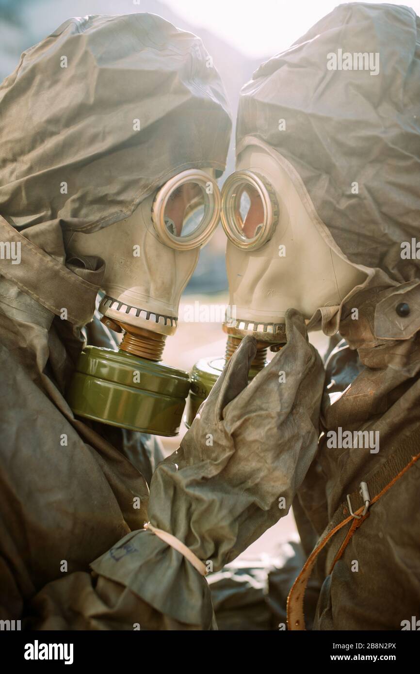 Portrait of couple in love in NBC protective suits and gas masks. Concept of preventive measures and protection for coronavirus COVID 19 pandemic and Stock Photo