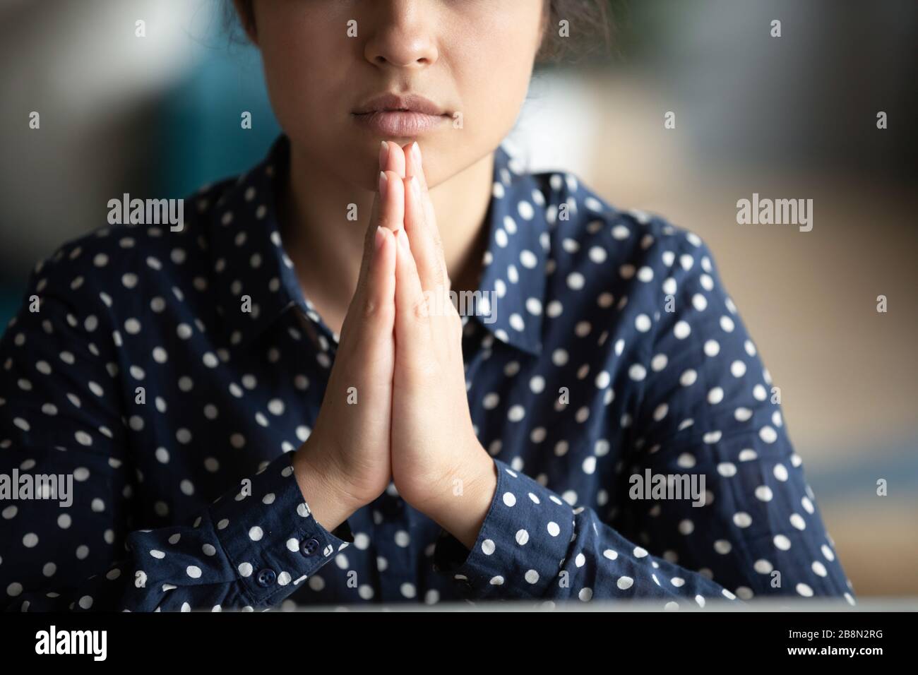 Close up mindful Indian woman putting hands in prayer Stock Photo