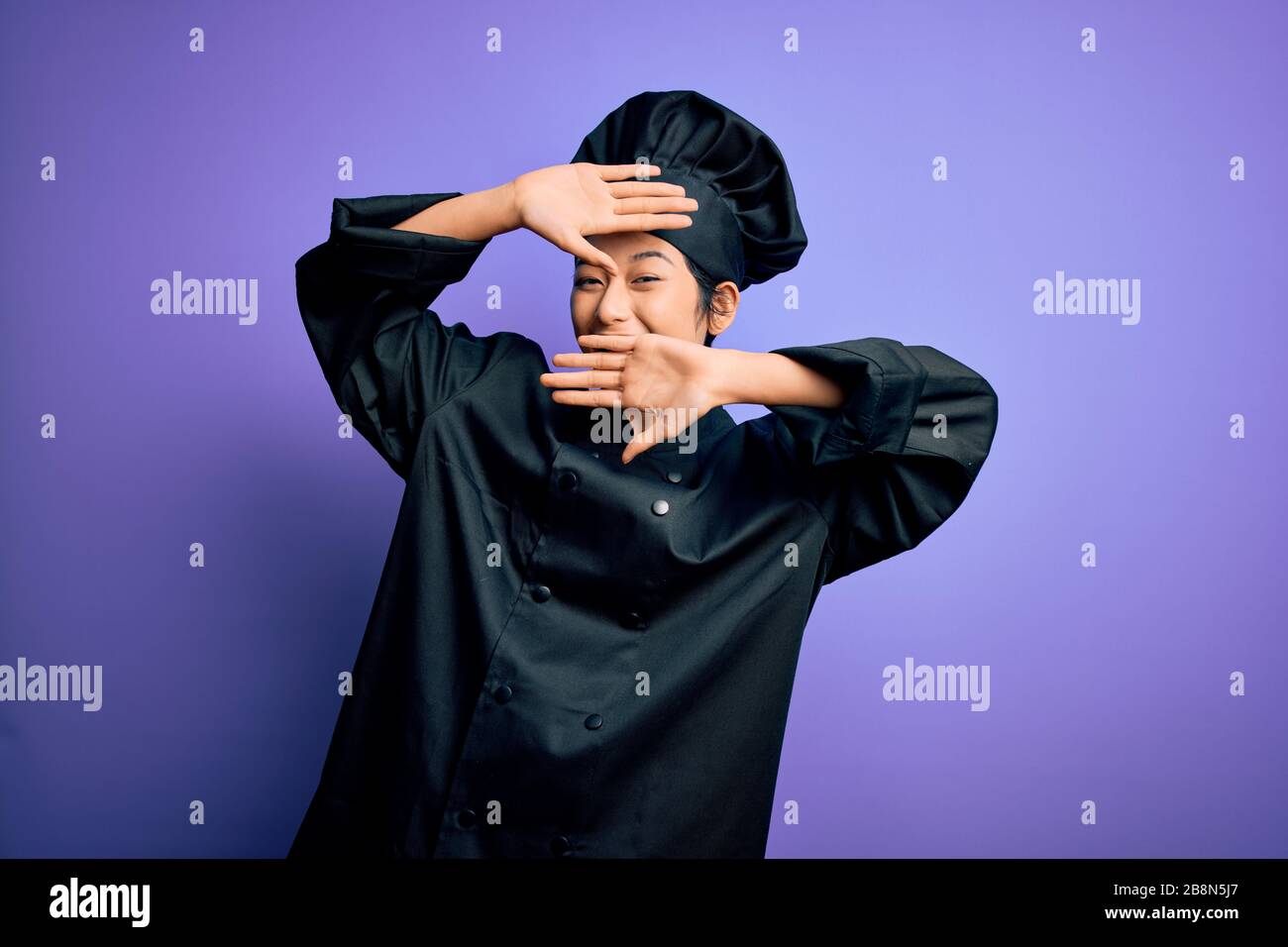 Young beautiful chinese chef woman wearing cooker uniform and hat over ...