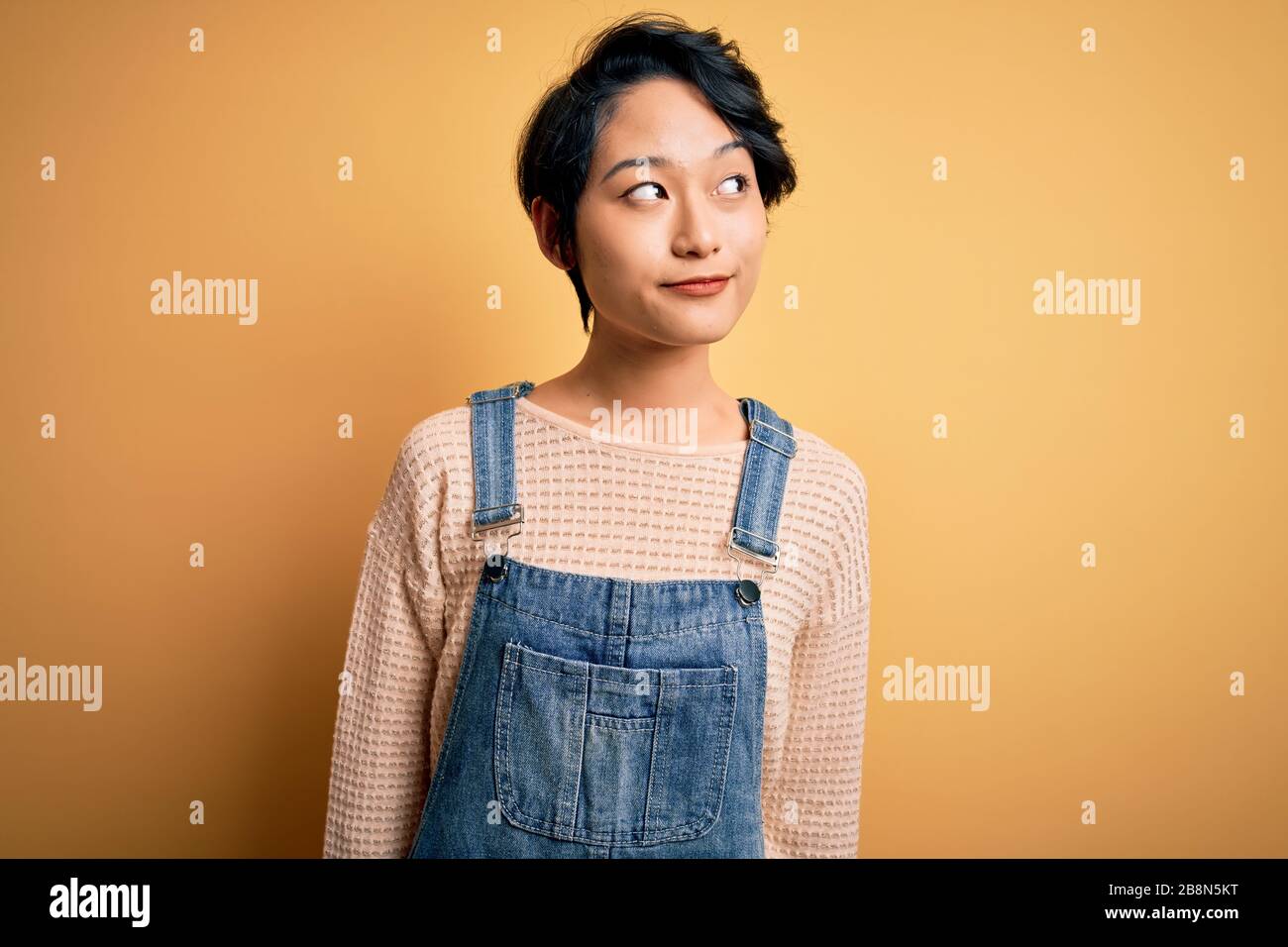 Young beautiful asian girl wearing casual denim overalls over isolated ...