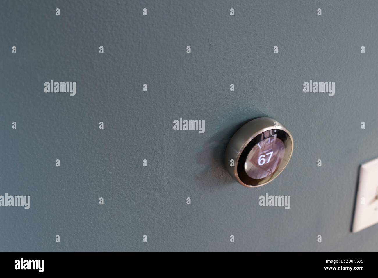 Smart home thermostat from google's nest. Green tech saving heating and cooling costs. Waste reduction Stock Photo