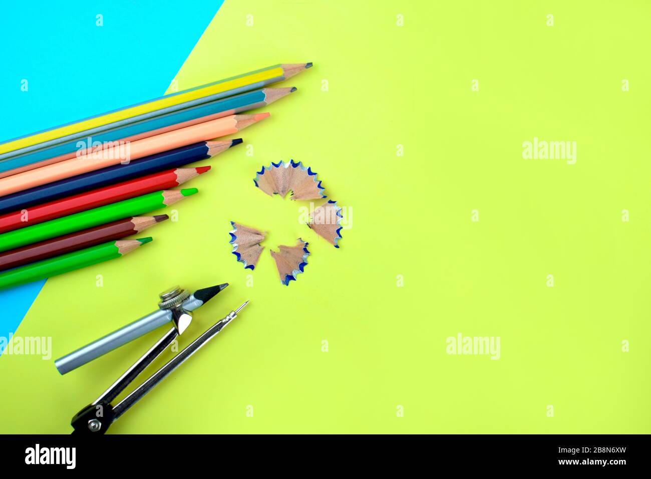 Eight different colored wood pencils and a pencil attached to a pencil compass pointing at a pencil shaving over a paper background Stock Photo