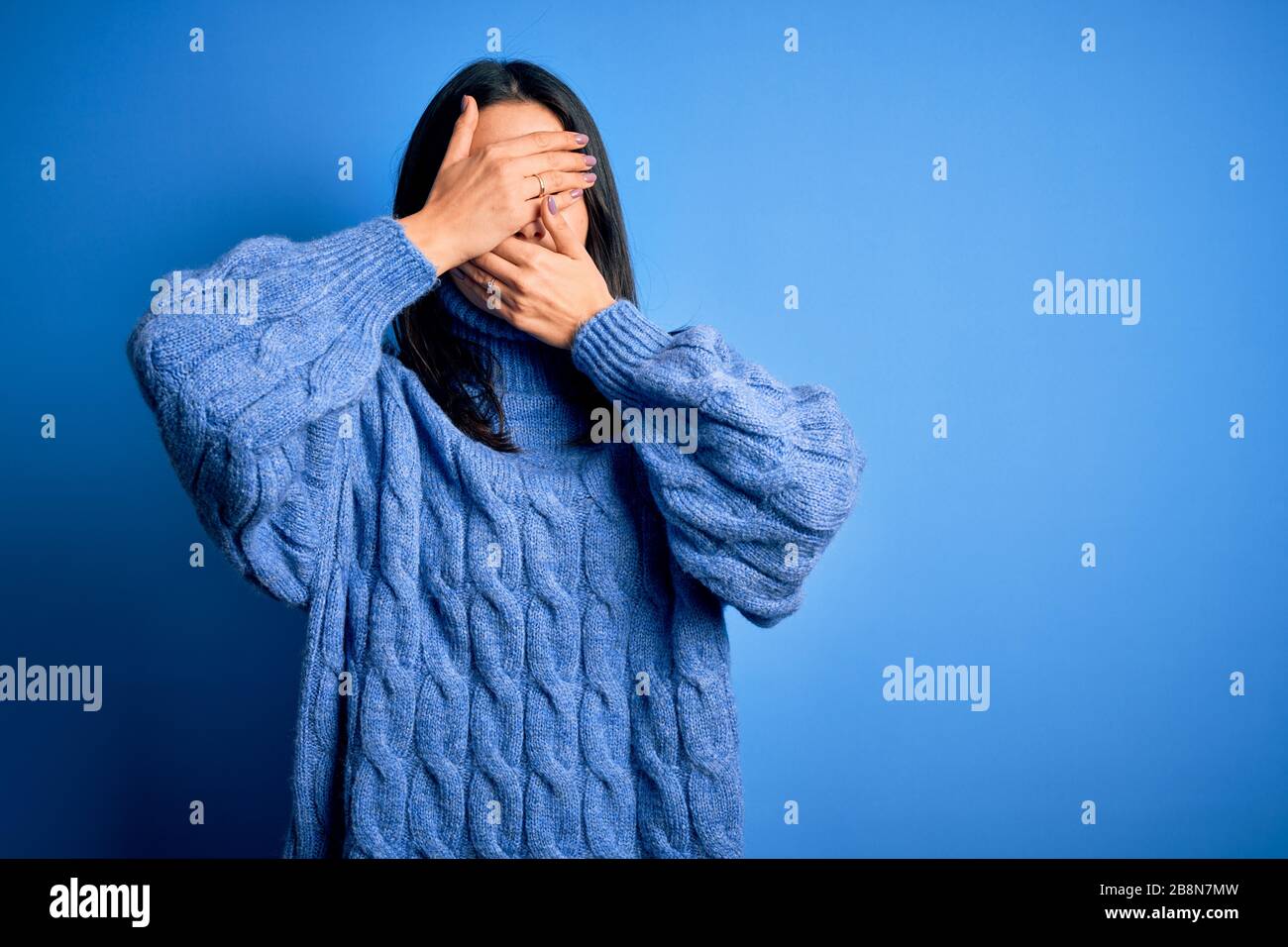 Young brunette woman with blue eyes wearing casual turtleneck sweater ...