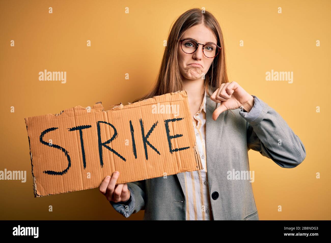 Young beautiful redhead woman holding banner with strike message over ...
