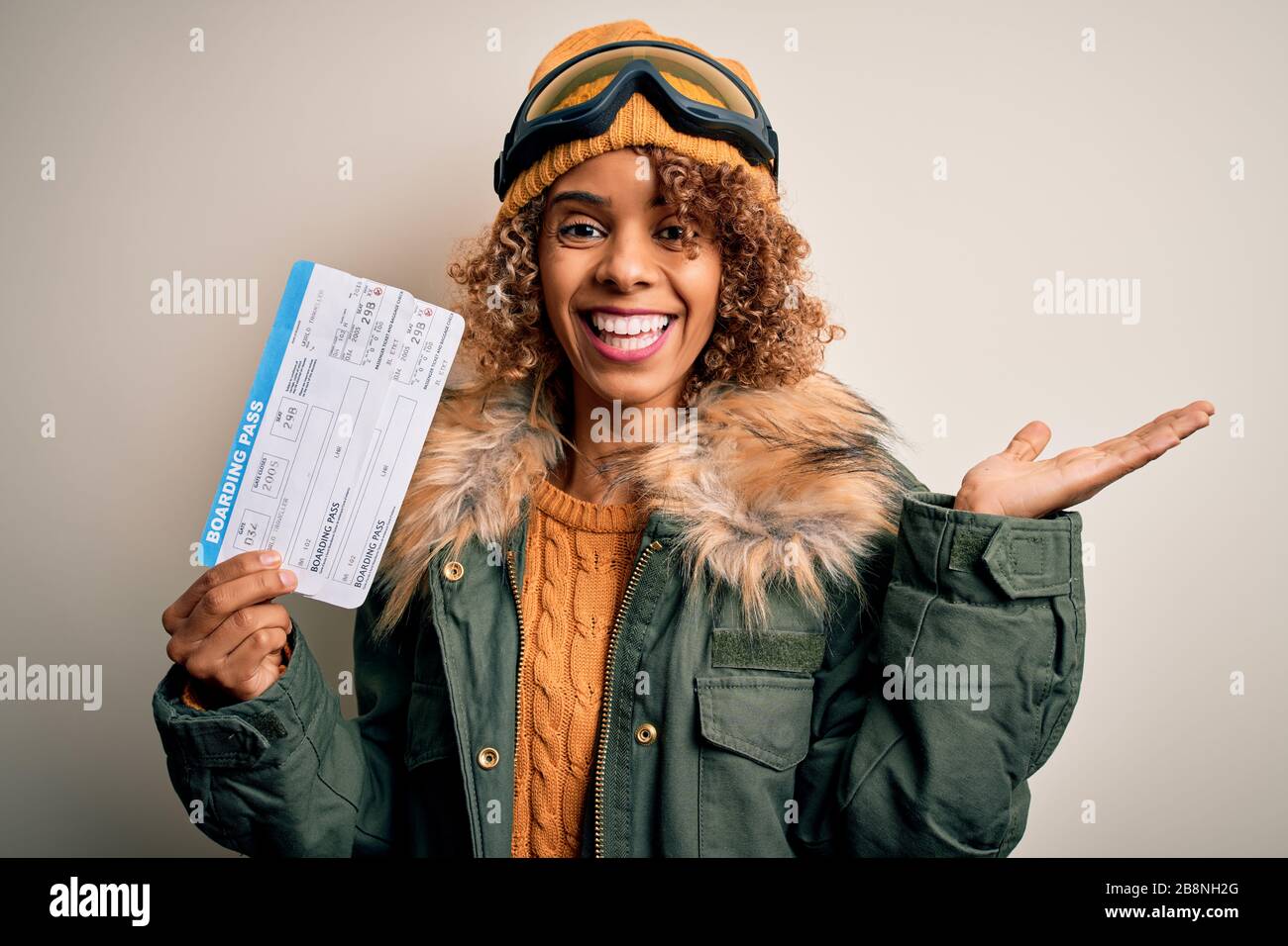 Young african american tourist woman wearing ski goggles holding plane