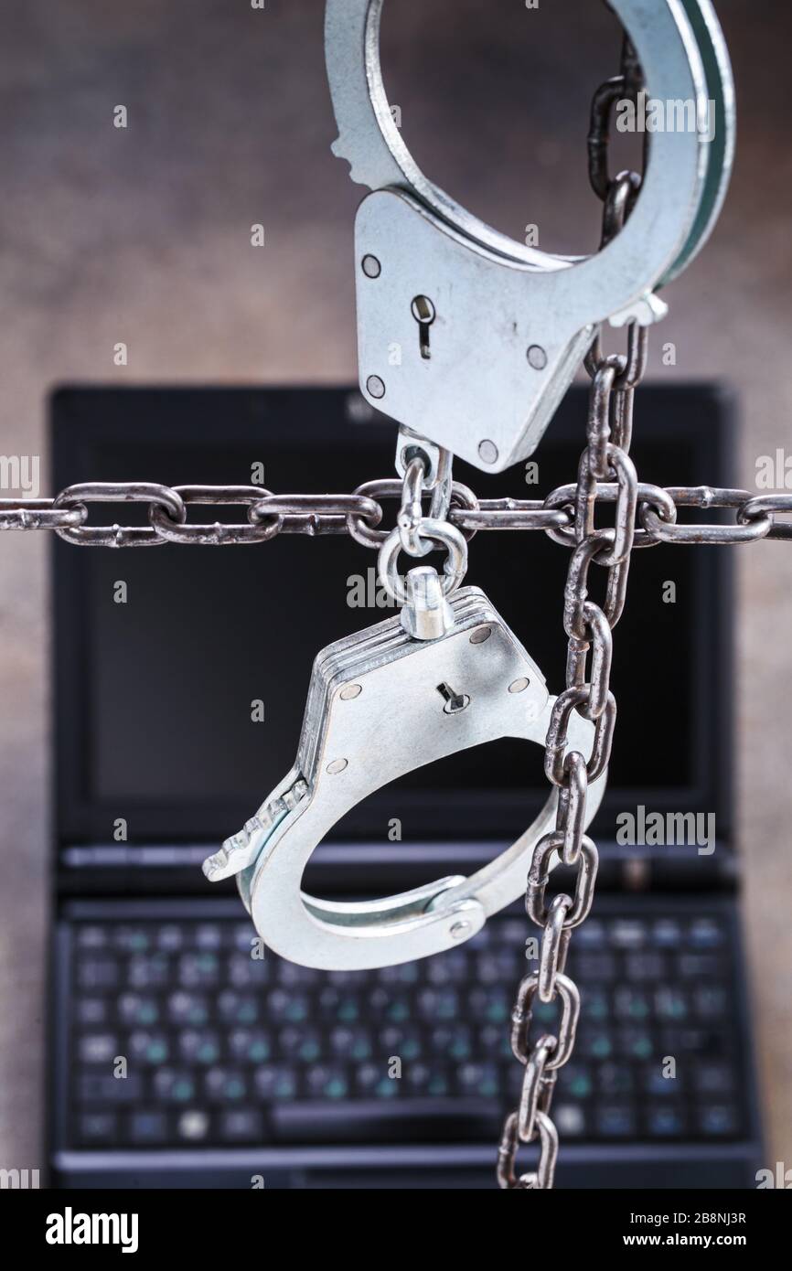 Laptop behind the handcuffs Stock Photo