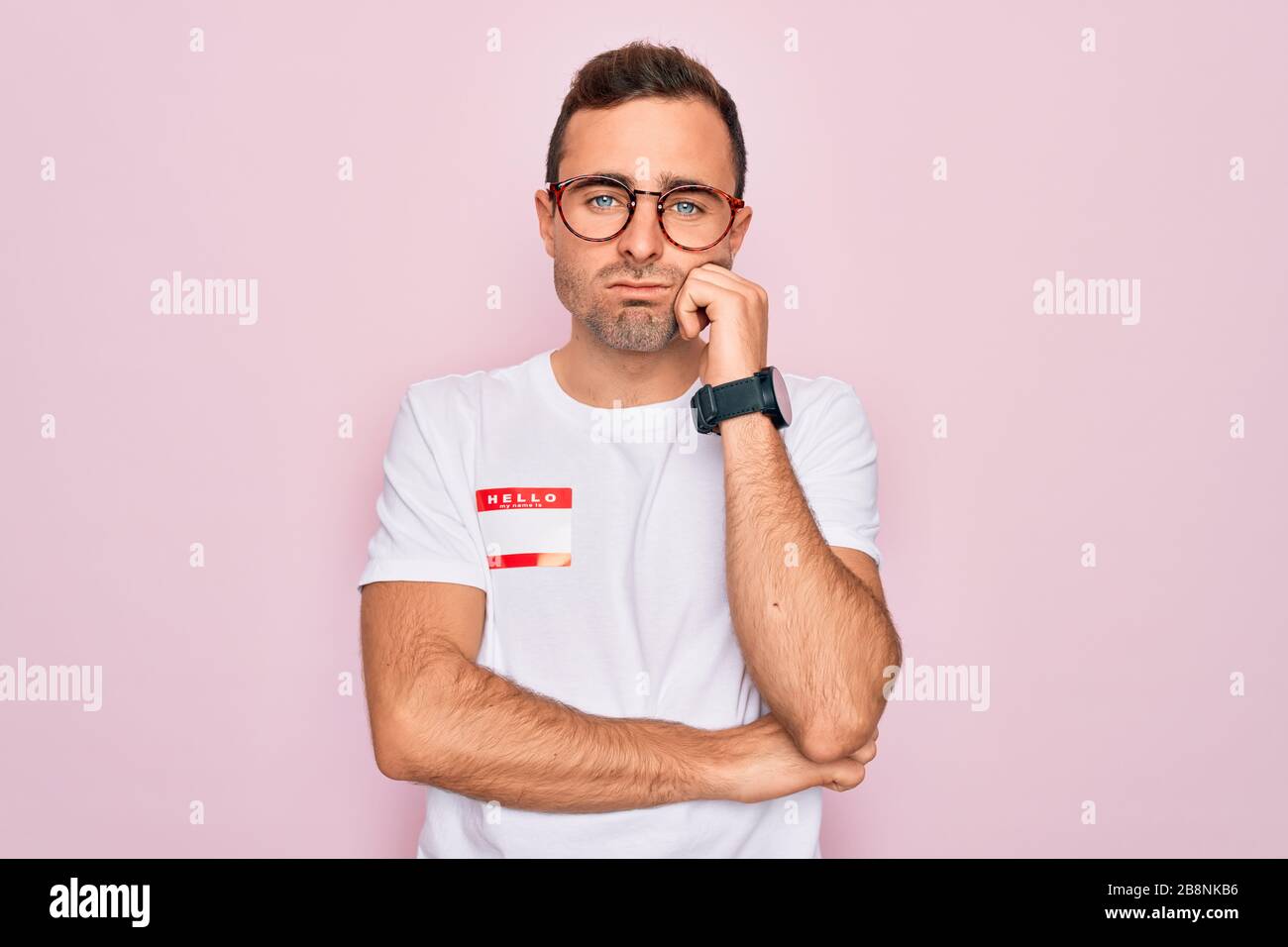 Handsome man with blue eyes wearing sticker with hello my name is ...