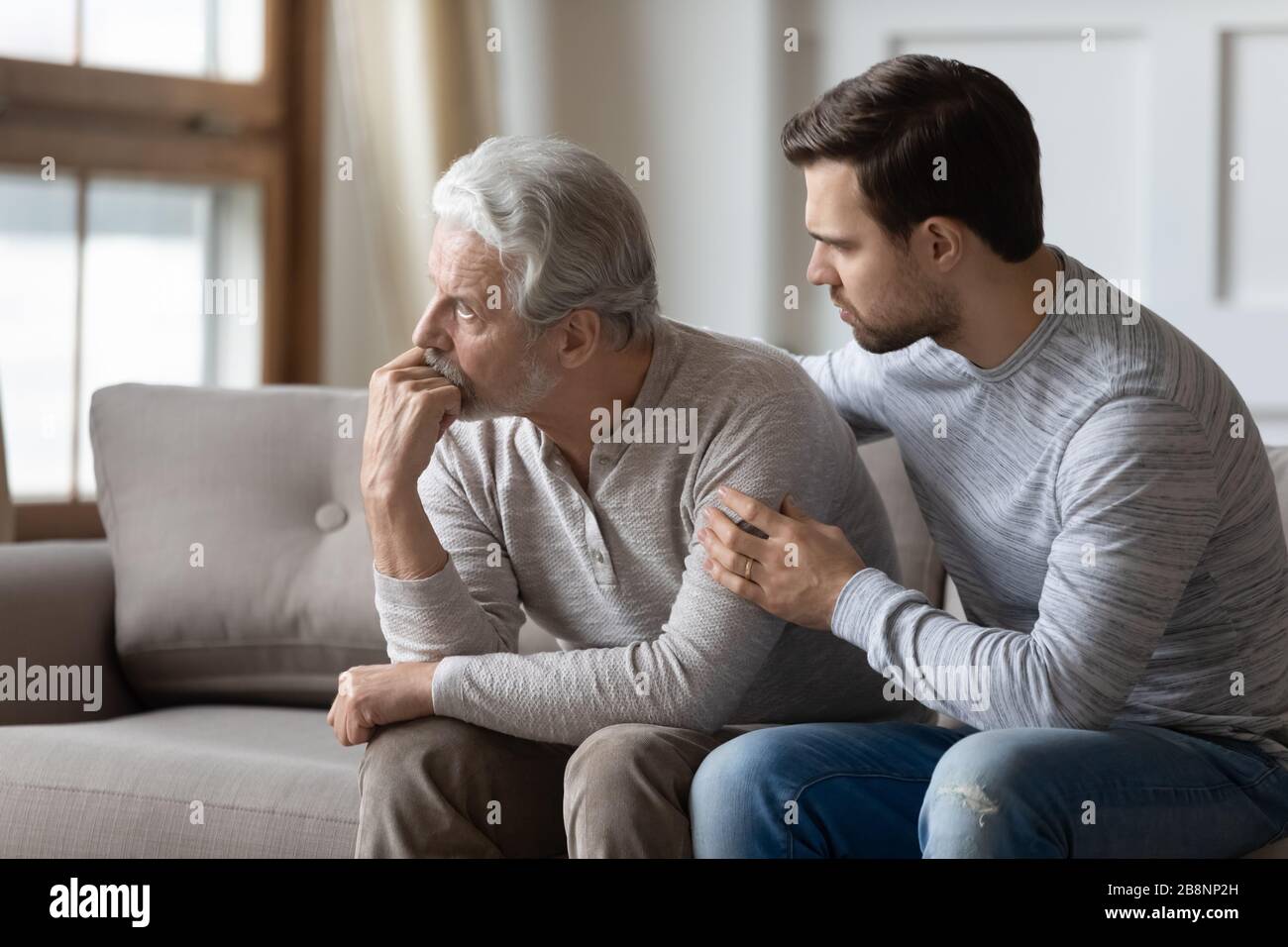 Loving adult son embrace support upset elderly father Stock Photo
