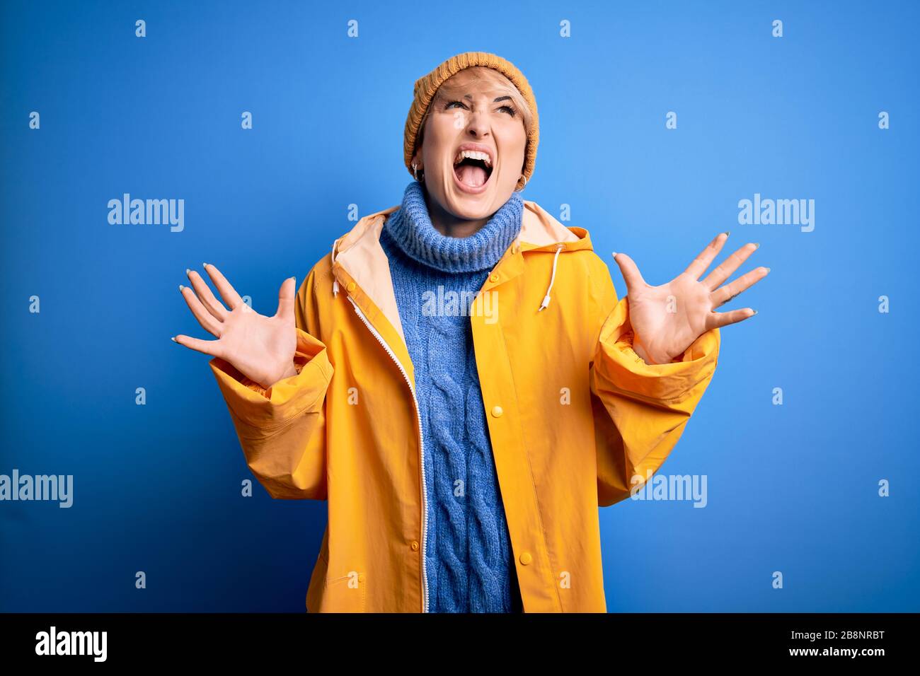 Young blonde woman with short hair wearing rain coat for rainy weather ...