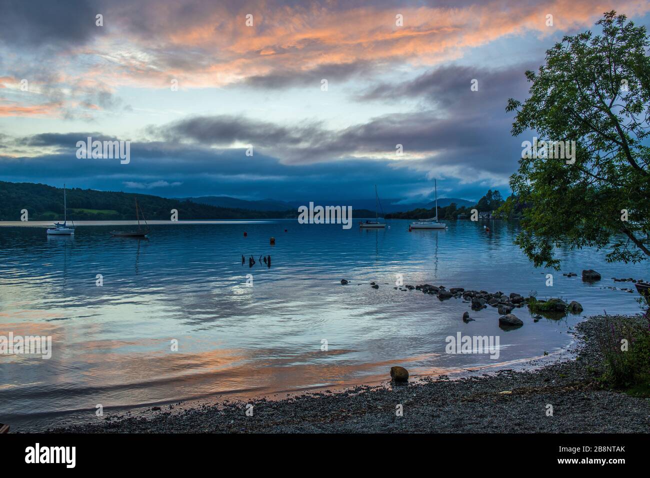 The Shore of Windermere on a Summer Evening with the red sky reflected on the shore of the lake - and not a soul around. Stock Photo