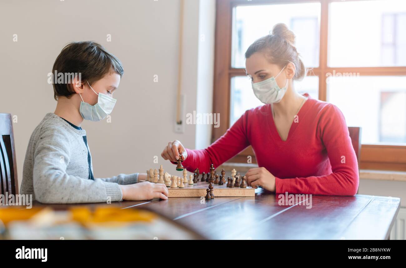 Mother and son playing chess to kill some time during curfew in crises Stock Photo