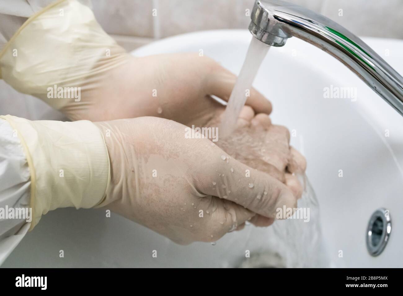 Surgeon washes and processes hands with white rubber gloves. Medical desinfection. Stock Photo