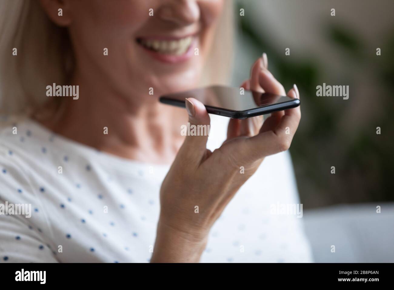Happy older woman using voice recognition function or virtual assistant. Stock Photo