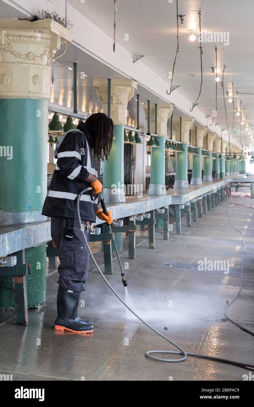Bryan, a maintenance worker with the market, sanitizes a closed arcade at Pike Place Market on Sunday, March 22, 2020. While many of the food-related businesses are open, the landmark’s non-essential businesses are temporarily closed including the market’s ubiquitous souvenir and flower stalls. Stock Photo