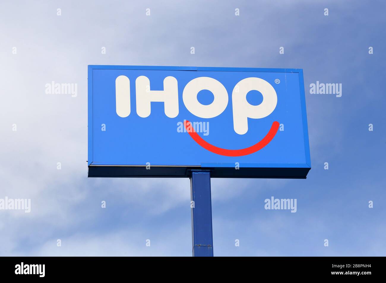 An IHOP sign on a pole against a cloudy day. Stock Photo