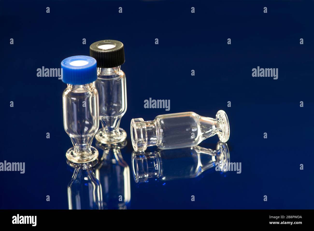 Chromatography autosampler glass vials with lids on blue. Stock Photo