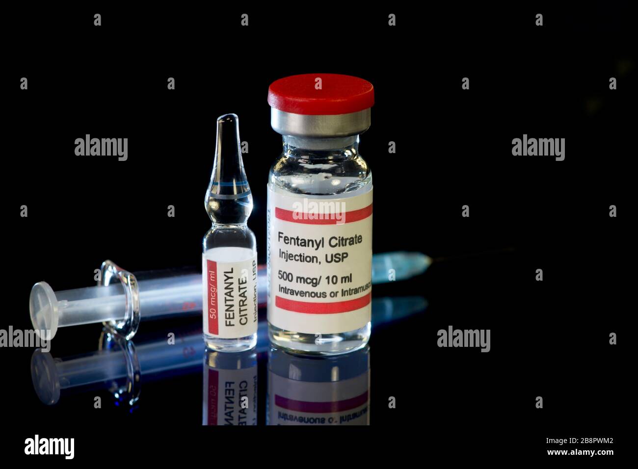 Fentanyl citrate vial and ampule with syringe on dark reflective surface. Stock Photo