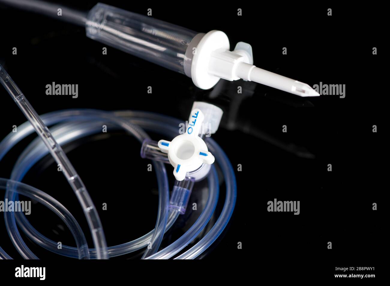 IV stopcock regulator with IV drip chamber and IV tubing on black. Stock Photo