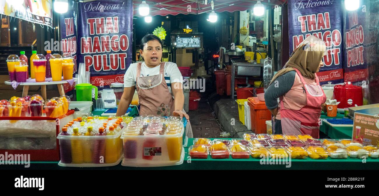 Two female stallholders standing behind counter of stall selling fresh fruit juice at Jalan Alor Bukit Bintang Kuala Lumpur Malaysia. Stock Photo