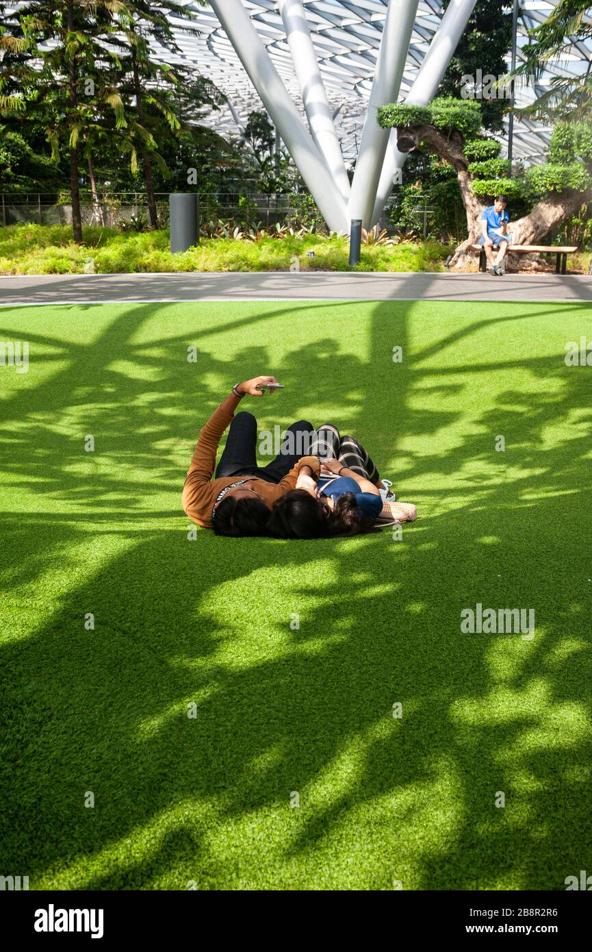 18.03.2020, Singapore, Republic of Singapore, Asia - A young couple lies down on artificial lawn at Foggy Bowls in the Canopy Park, a playground. Stock Photo