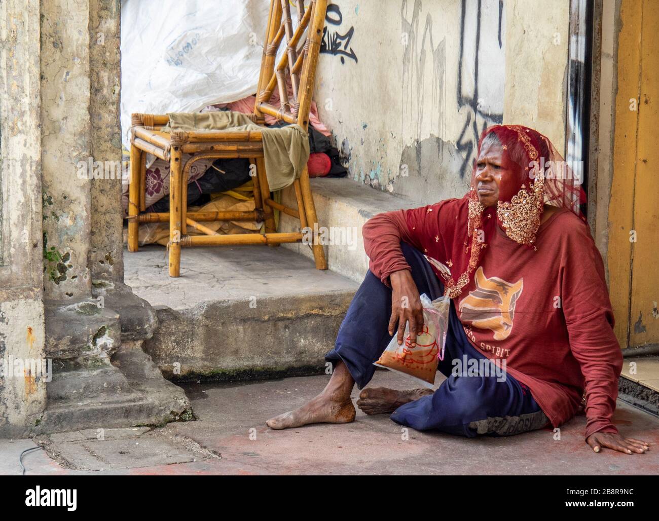 Middle age woman sitting on the pavement  in front of her home in Chinatown Kuala Lumpur Malaysia. Stock Photo