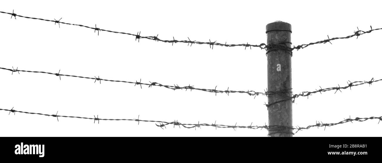 three lines of sharp barbed barb wire security fencing converging on a post. large void for text or cropping. bw black and white Stock Photo