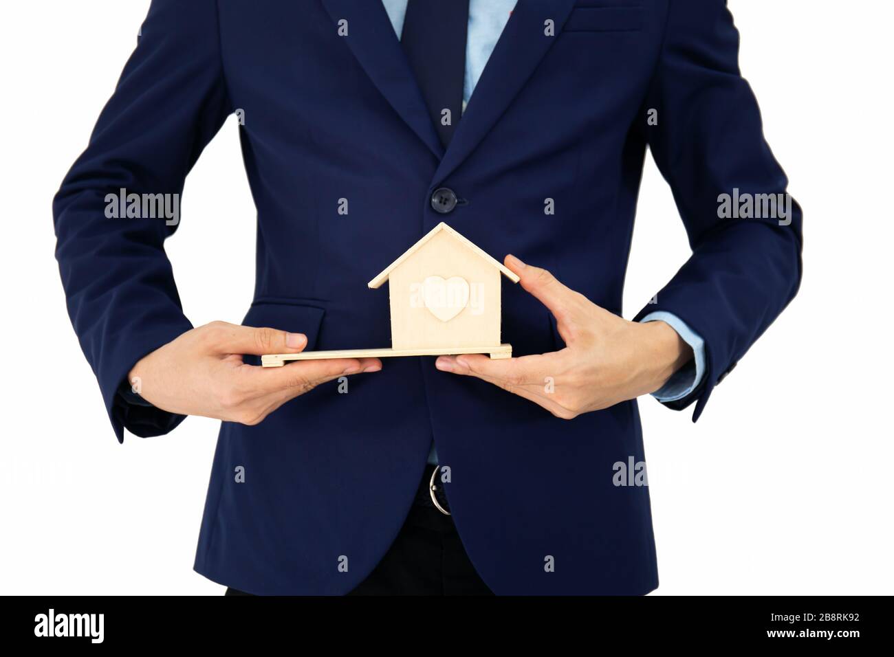 Businessmen stand and hold A small wooden house in his hand and isolated on white background Stock Photo