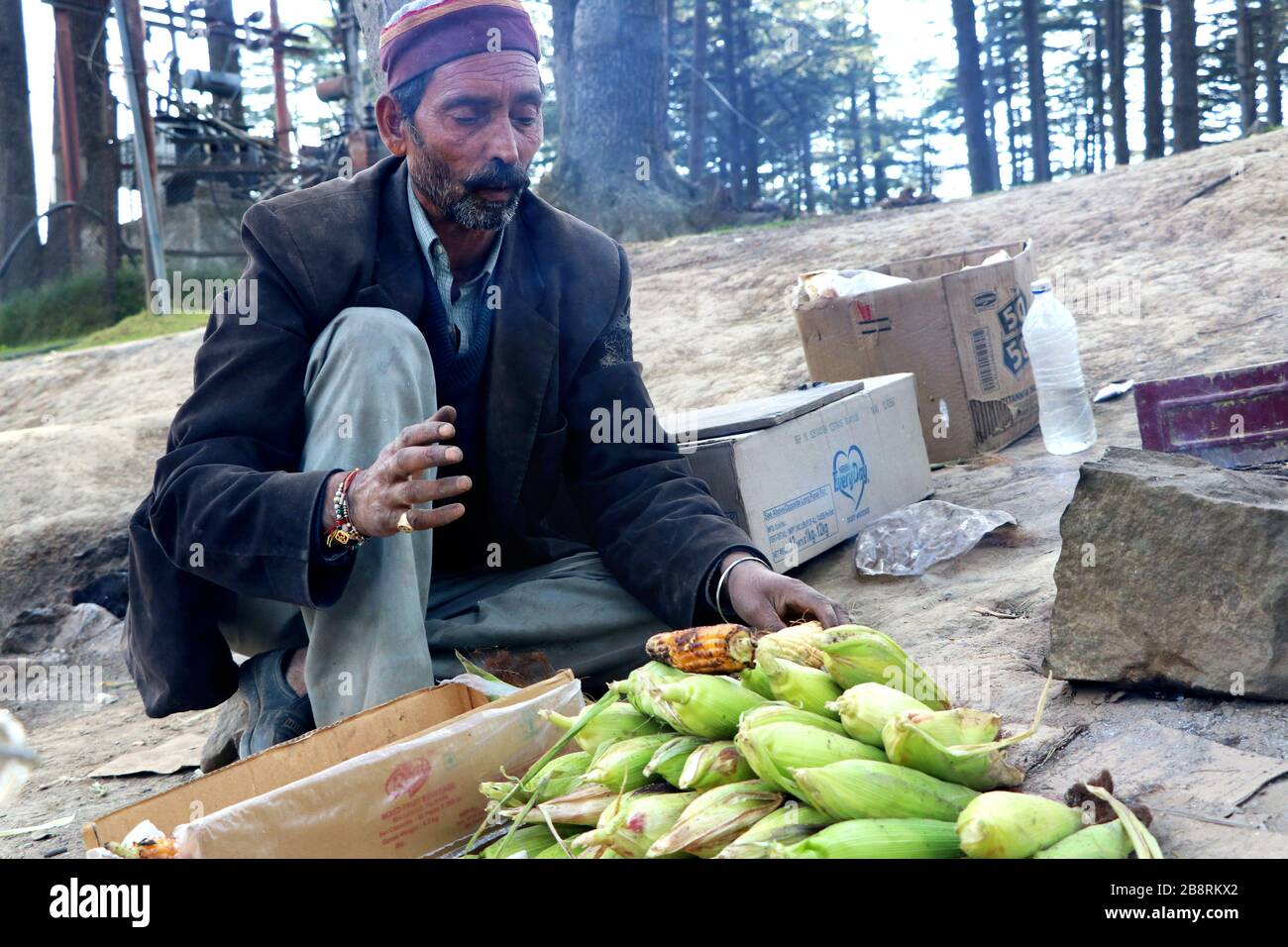 An Indian old man sale Bhutta (Fire Roasted Corn) street food at Katra, Jammu, India - 17 october, 2018 Stock Photo