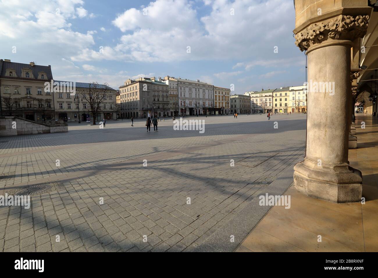 Krakow / Poland - 19 March 2020: Almost empty main market square  to prevent spreed of coronavirus, Saint Marys church, dry hotspot in popular city Stock Photo