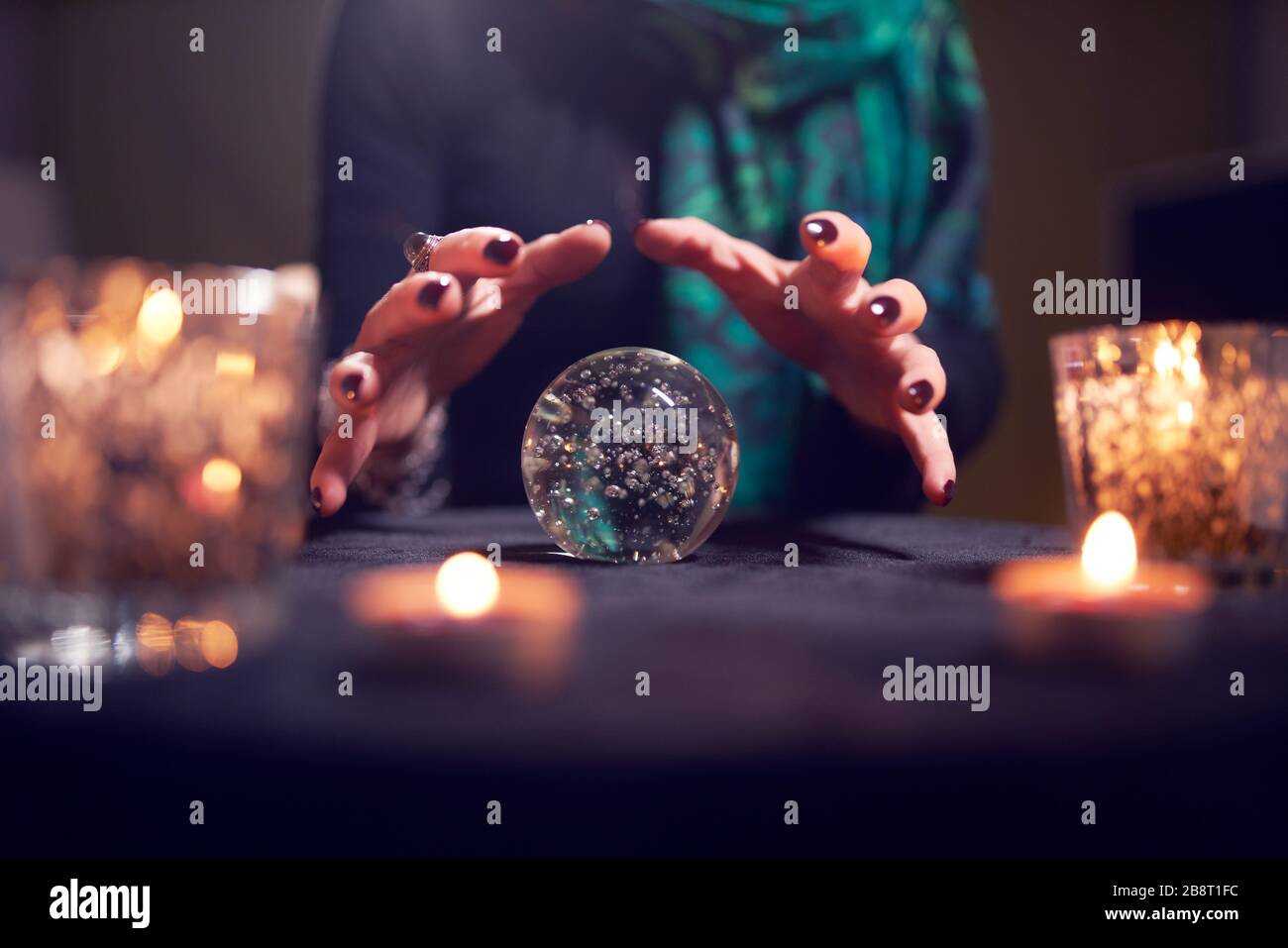 Close-up of fortune-teller's hands with ball of predictions in dark room Stock Photo