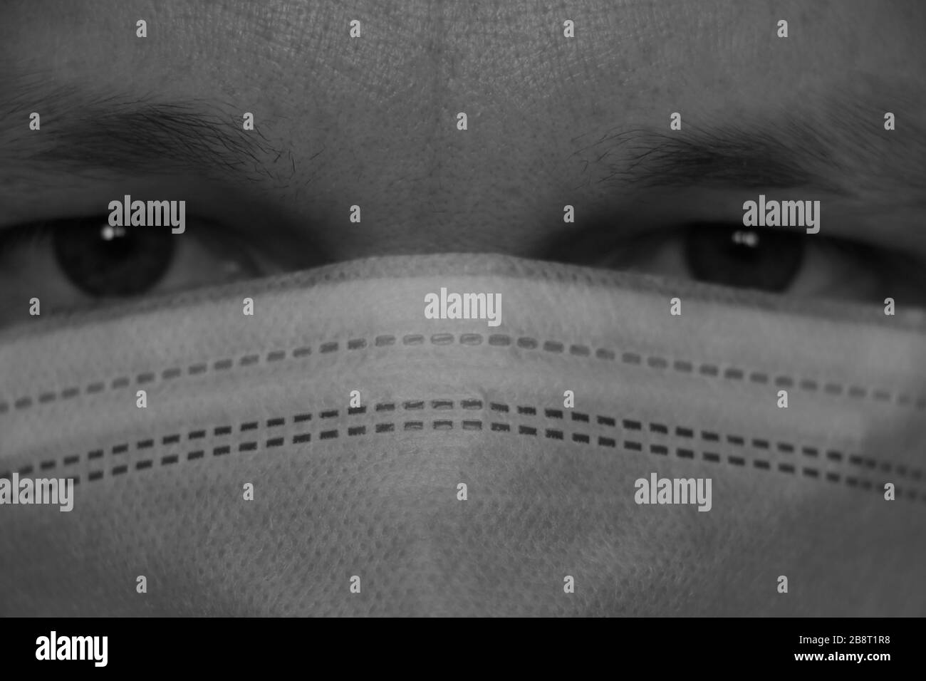 The man has a medical protective mask, anti-infection, protection against coronavirus. Strong look at the camera, close-up. Pandemic epidemic Stock Photo