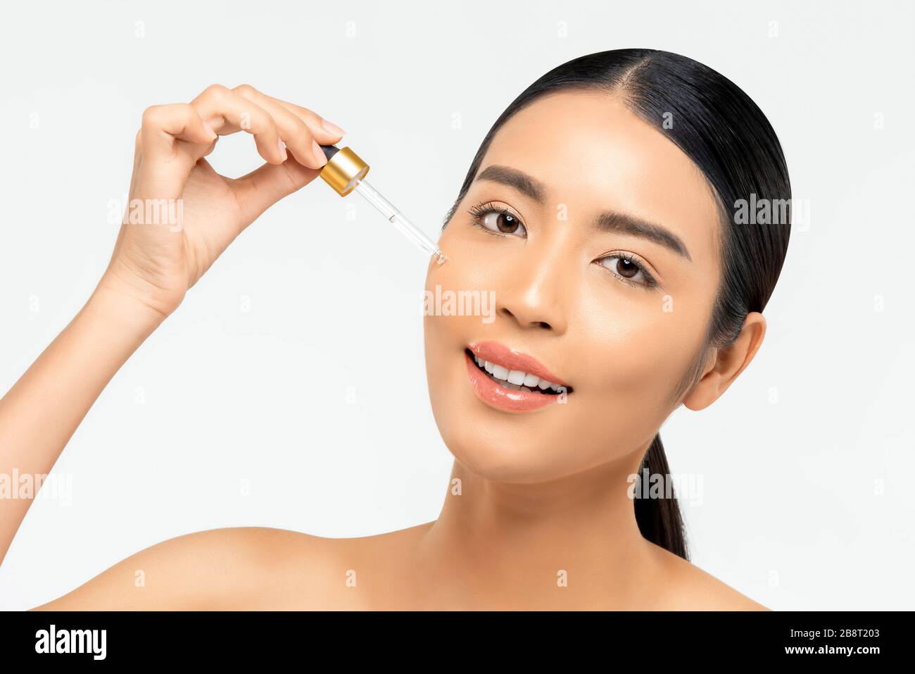 Beautiful Asian woman applying anti aging moisturizing serum on her face for beauty and skin care concepts Stock Photo