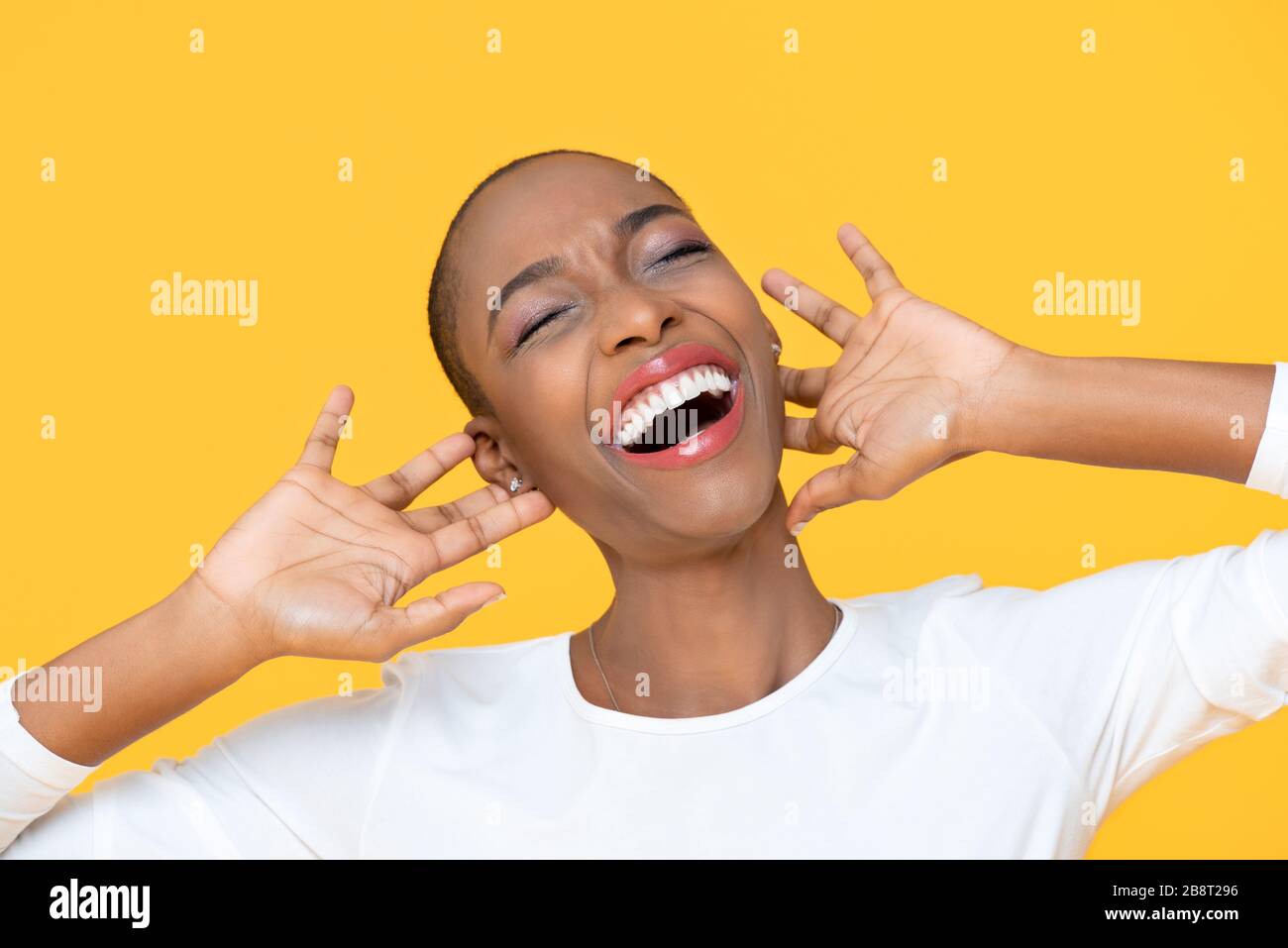 African American woman laughing with joy expressing happiness and fun on yellow background Stock Photo