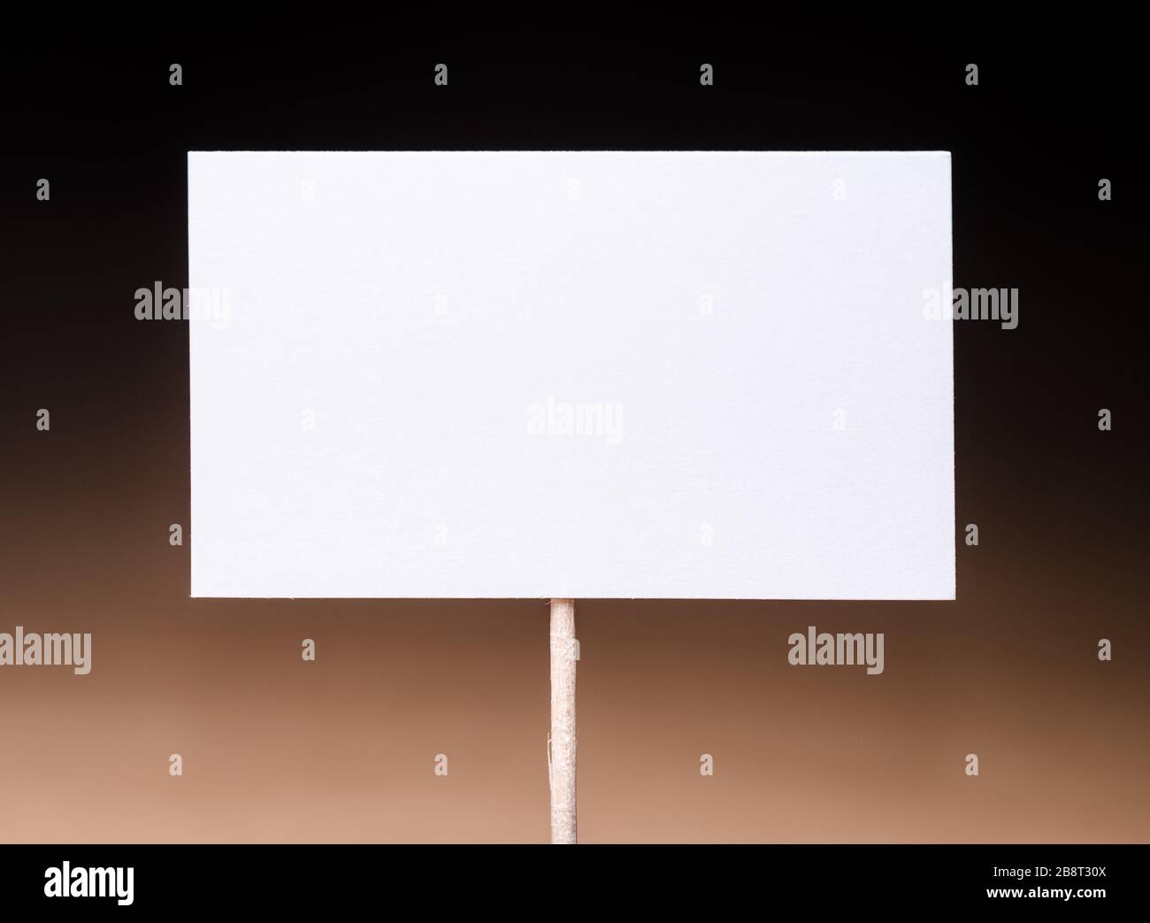 Blank, empty, white cardboard sign on wooden stick against dark background, space for text, copy space Stock Photo