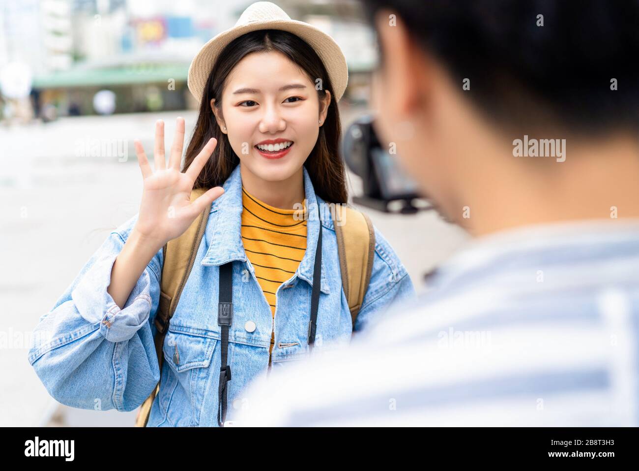 Smiling beautiful Asian woman tourist travel vlogger say hi to camera in the city Stock Photo