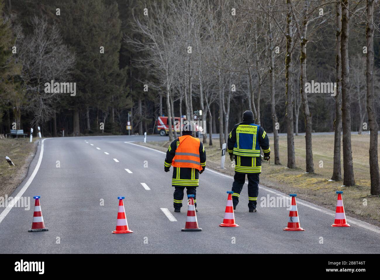 Neustadt Am Rennsteig, Germany. 23rd Mar, 2020. Firefighters block the road one kilometre before Neustadt am Rennsteig. After six of the eleven cases of Covid-19 in the Ilm district came from the village in the rural community of Großbreitenbach, the village was completely quarantined for two weeks. Credit: Michael Reichel/dpa-Zentralbild/dpa/Alamy Live News Stock Photo