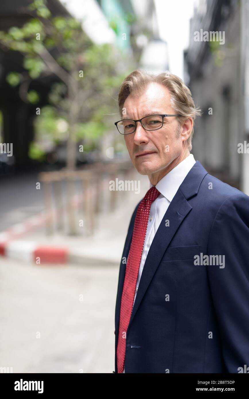 Profile view of handsome mature businessman wearing suit in the city ...