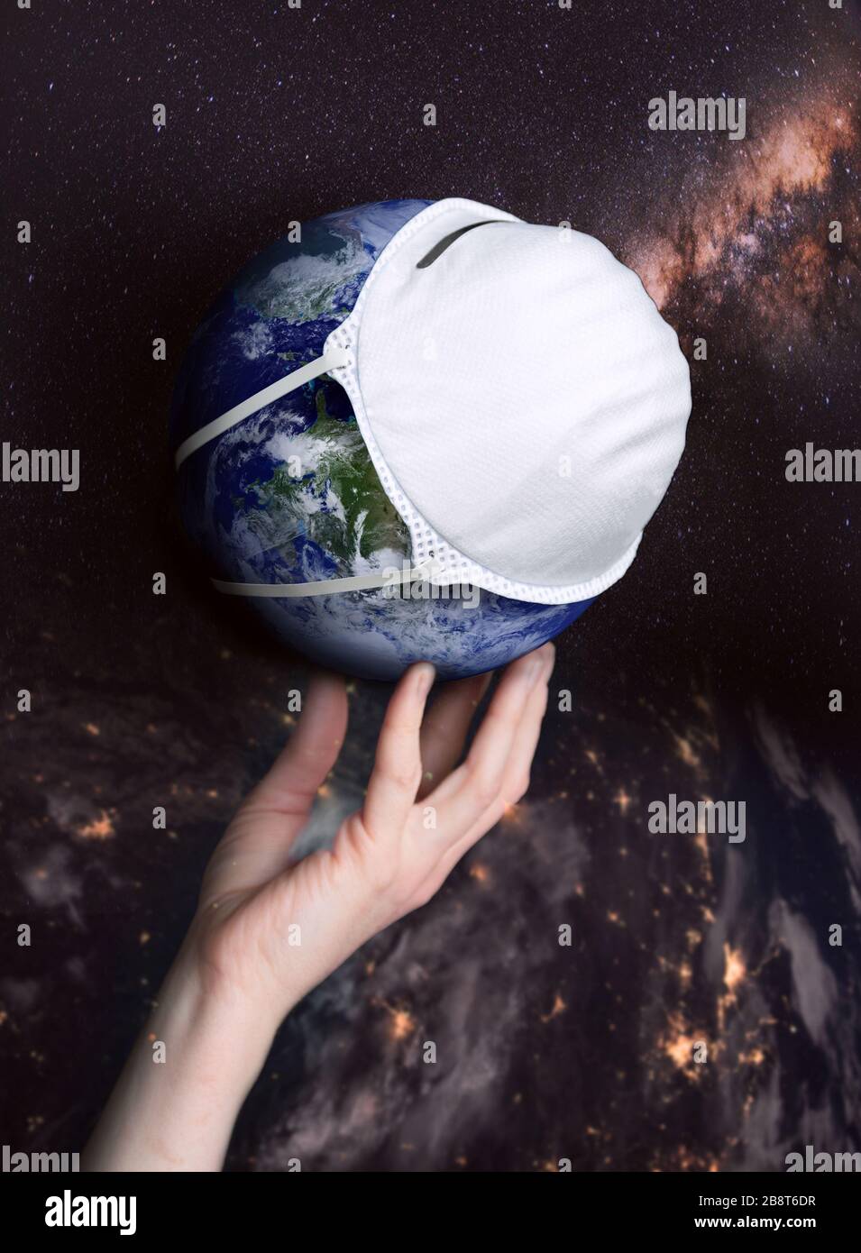 A hand holds the globe with a medical mask during an epidemic of Covid 19 or coronavirus worldwide. Concept Stock Photo