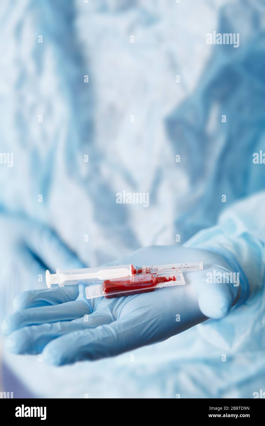 Close up of doctor hand holding syringe and blood sample. Medical